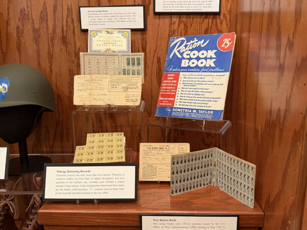 IMG_4677 - Experience Camden, South Carolina Museum display of vintage wartime ration books and pamphlets mounted on a wooden wall.