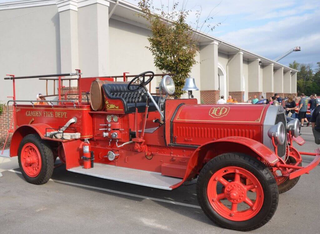 firefestantique - Experience Camden, South Carolina A vintage red fire truck labeled Camden Fire Dept. is parked outside a building, with people standing nearby and a tree in the background.