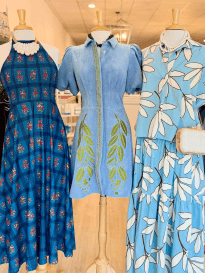pinkstable2026 - Experience Camden, South Carolina Three mannequins display dresses: one in a blue floral halter dress, one in a blue short-sleeve dress with green leaf details, and one in a light blue and white leafy-patterned dress with a matching top.