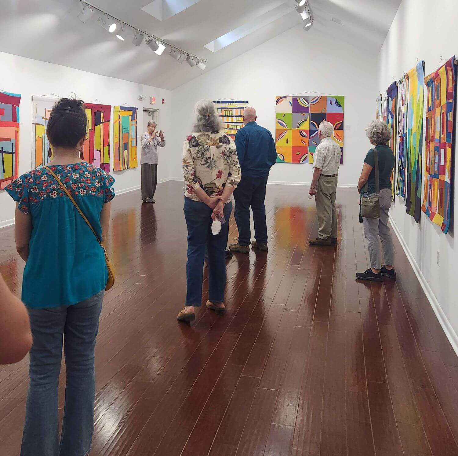 bassett gallery - Experience Camden, South Carolina A group of people stands in the Bassett Gallery looking at colorful abstract fabric wall hangings while a guide speaks to them.